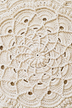 A close-up of a cream-colored crocheted floor rug with an intricate floral and scalloped lace pattern.